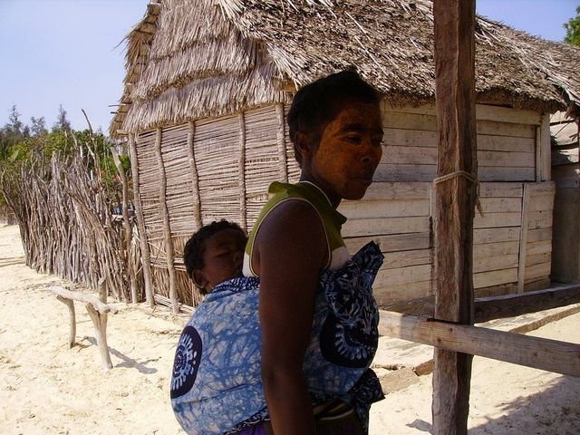 Femme et enfants devant une case