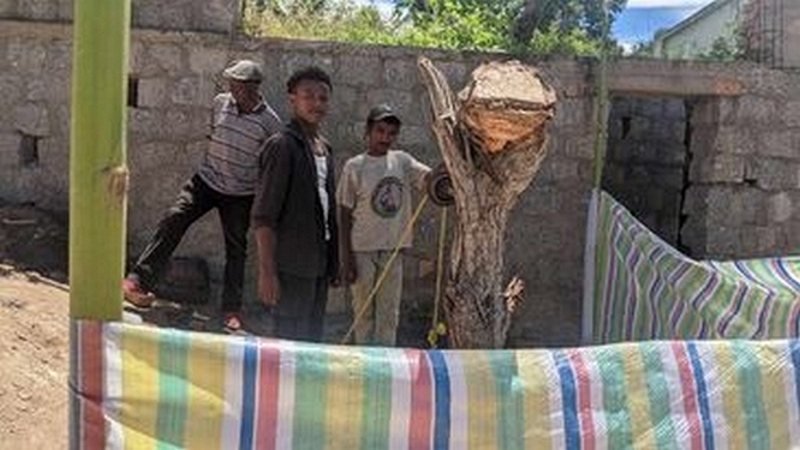 Two men digging one of the boreholes by hand, earth piled beside them