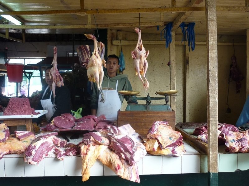 Étal de boucherie en plein air, viande suspendue à des crochets
